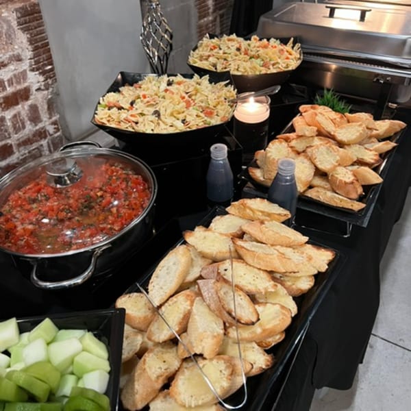 A buffet spread with pasta salad, bruschetta, tomato bruschetta topping, and chopped melon at Mary's Bagel Café.
